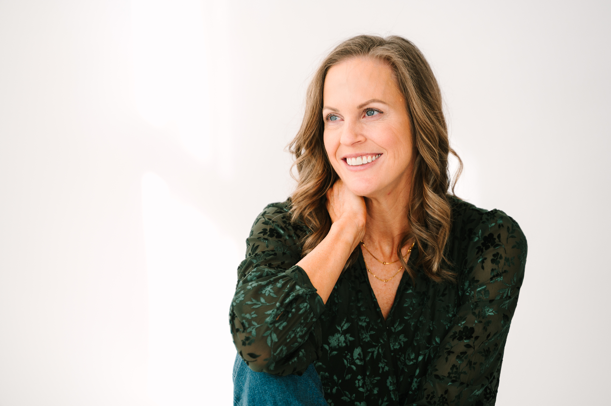 Lydia Fine sitting on floor in a green shirt with her hand on her neck