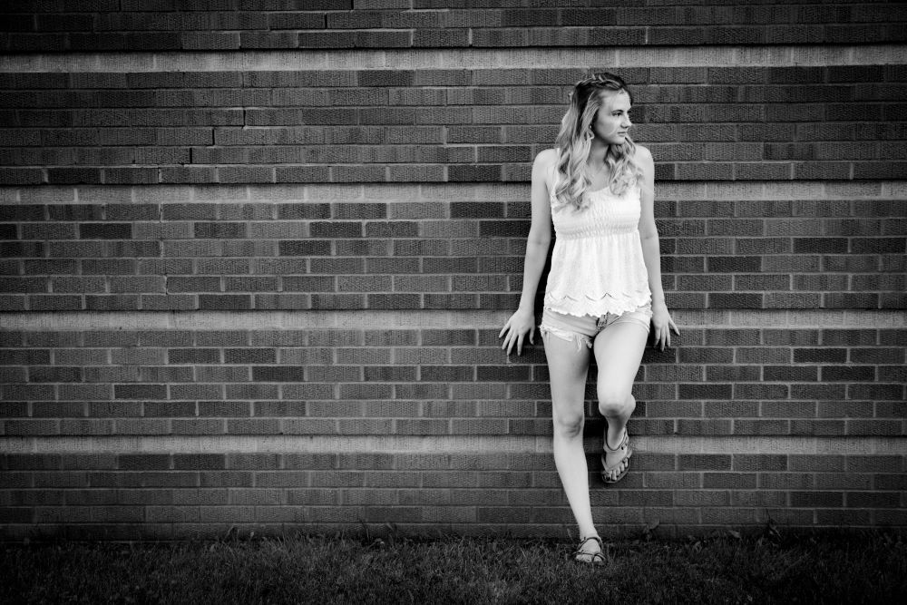 Senior girl leaning against a brick wall